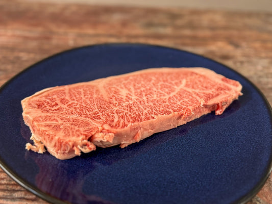 Rohes Wagyu A5 Steak aus Japan, mit intensiver Marmorierung, serviert auf einem blauen Teller – exklusiv bei The Meat Boutique.