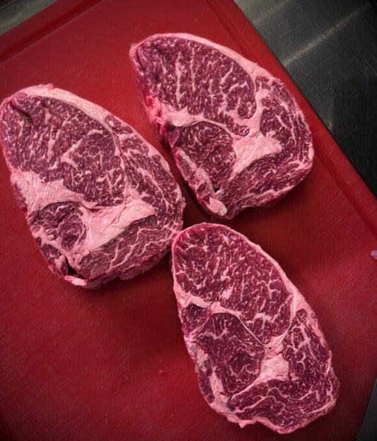 Dry-aged Ribeye Steak von einer polnischen Hereford-Färse – 30 bis 60 Tage gereift, mit perfekter Marmorierung und intensiver Farbe auf rotem Schneidebrett präsentiert.